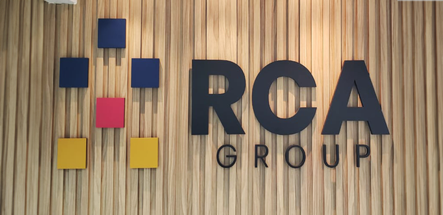 Letreiro RCA Group na parede de madeira da recepção